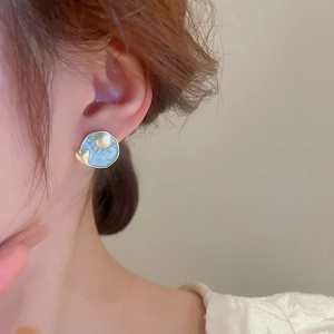 Close-up of enamel heart earrings featuring sun and moon relief in sky blue and gold