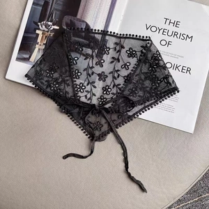 Detail of black triangle lace hair scarf with floral embroidery and pom-pom edges