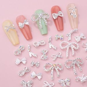 Macro shot of 3D bow nail art charms with rhinestones and pearls on colorful false nails