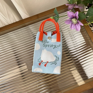 Detail of Hello Spring knitted bag featuring cloud pattern and orange round handles