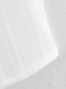 Detailed close-up of white knitted fabric with vertical texture and wavy decorative stitching