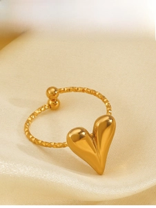 Detailed close-up of an 18K gold heart-shaped open ring with faceted band on silk fabric
