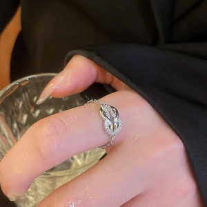 Detail view of silver horseshoe chain ring with pavé zircons worn on hand against black suit