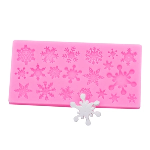 Detail of pink silicone snowflake mold showing various patterns and finished white resin crafts