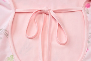 Dettaglio dello scollo dell'abito floreale rosa con fiocco e trama in maglia elastica
