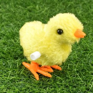 Close-up of yellow plush clockwork chicken toy on green grass with soft texture details
