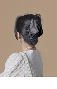 Détail d'une pince à cheveux en satin noir élégant portée sur les cheveux, fond dentelle