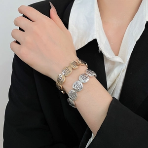 Detail of gold and silver religious coin bracelets with inspirational scripture engraving