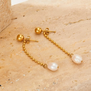 Elegant gold chain tassel pearl drop earrings on a textured stone background