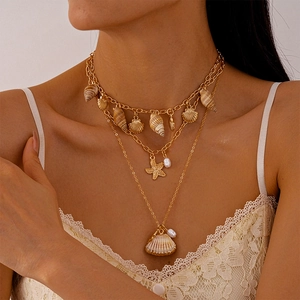 Detail of layered gold ocean necklace with starfish shell charms on a model