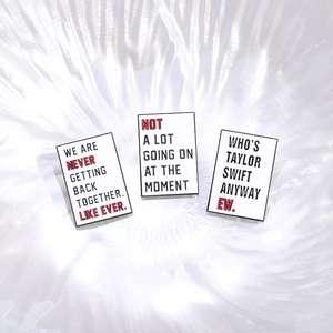 Three white enamel rectangle pins featuring fun English quotes on a reflective surface
