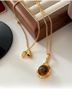 Macro view of gold necklace featuring teardrop pendant with round brown gemstone