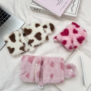Close-up of three cute plush heart-pattern pouches with zippers and snap closures