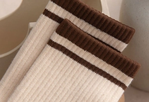 Macro shot of beige cotton socks featuring double dark brown stripes on the ribbed cuffs