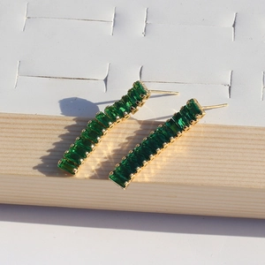 Close-up of golden hoop earrings featuring rectangle emerald green zircon stones