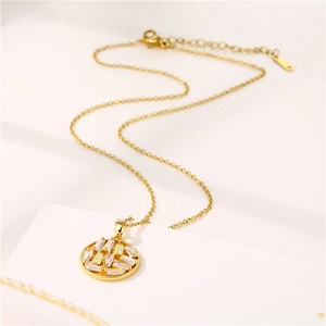 Collana dorata con pendente rotondo geometrico e zirconi incastonati su fondo beige
