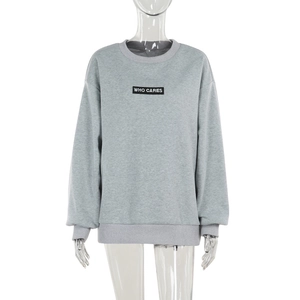 Détail du sweat gris à col rond avec imprimé 'WHO CARES' et poignets côtelés
