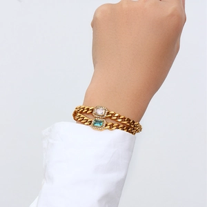 Detail showing gold Cuban chain bracelets with blue and white rectangular gemstones