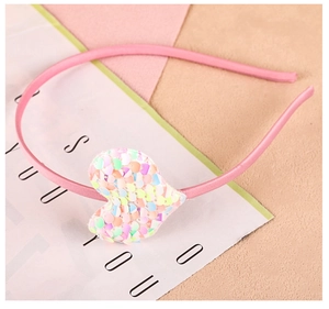 Détail d'un serre-tête en satin rose avec décoration en cœur et paillettes brillantes