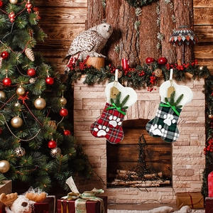 Detail of bone-shaped plaid Christmas stockings with paw prints on a festive mantel