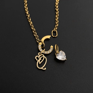 Close-up of gold stainless steel necklace with CZ-paved C and Q charms and heart pendant