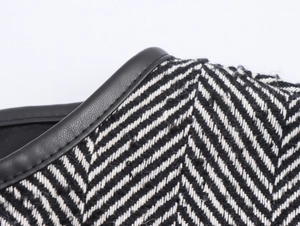 Close-up of black and white herringbone fabric with premium black leather trim and stitching