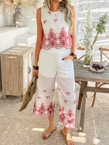 Detail of red floral embroidery on a white sleeveless top and cropped pants set