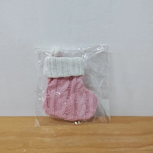 Close-up of pink and white knitted Christmas stocking decoration in clear packaging
