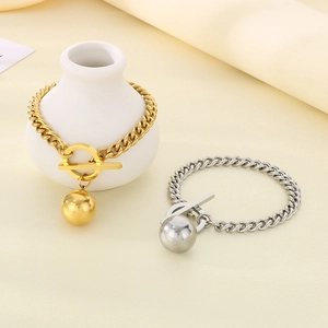 Dettaglio di bracciali a catena cubana oro e argento con ciondoli a sfera e chiusura a T