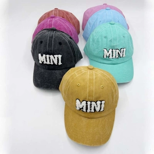 Flat lay of multiple washed cotton baseball caps with MINI embroidery in various colors