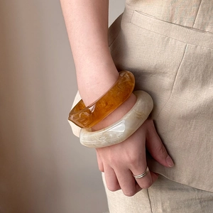 Maillard irregular wide resin bangles in amber and cream white on model's wrist