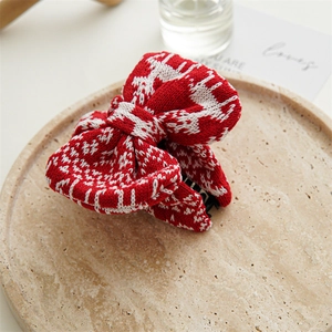 Close-up of a festive red and white knitted bow hair claw clip with a winter pattern
