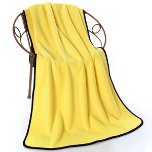 Absorbent coral fleece pet towel in bright yellow hanging on a rattan chair