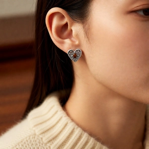 Close-up of vintage heart-shaped stud earring with brown zircon and ornate silver carving