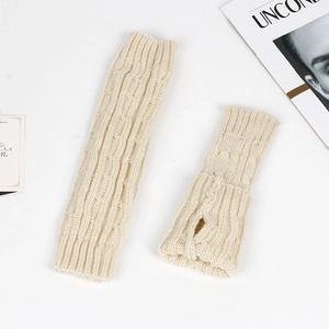 Detailed macro of beige cable-knit arm warmers featuring thumb hole and soft yarn texture