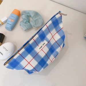 Detailed close-up of a blue and white checkered fabric cosmetic bag with a zipper