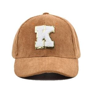 Details der braunen Cord-Baseballkappe mit großem weißen Frottee-K-Stickaufnäher auf der Front