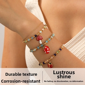 Vue détaillée d'un ensemble de 4 bracelets perlés colorés avec breloques fraise et champignon