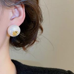 Vue détaillée d'une boucle d'oreille perle avec le caractère chinois porte-bonheur