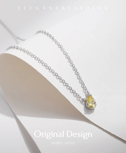 Macro detail of S925 sterling silver necklace with pear-cut yellow gemstone on white paper