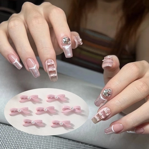 Pink 3D ballet bow nail charms with pearls shown on French manicure mirror nails