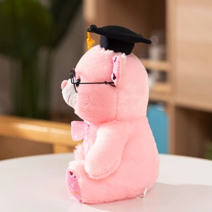 Close-up of pink graduation plush bear with black cap and yellow tassel on white table