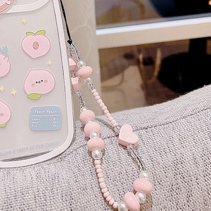 Macro shot of pink heart beads and pearls on phone strap with cute peach case