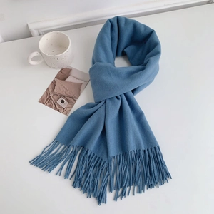 Flat lay of soft blue cashmere-style knitted scarf with tassels and coffee cup