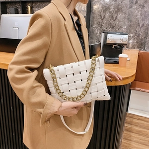 White woven leather handbag with gold chain detail on elegant model in cafe