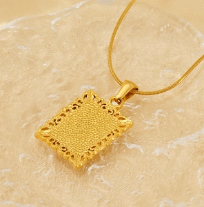 Close-up of golden vintage textured rectangular pendant on a snake chain over ice crystals
