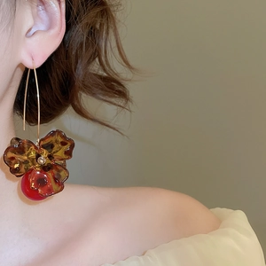 Detailed side view of vintage flower earrings with amber resin and red pearl charms
