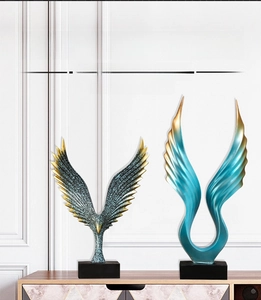Detailed resin angel wings and eagle wing statues on a modern wooden sideboard