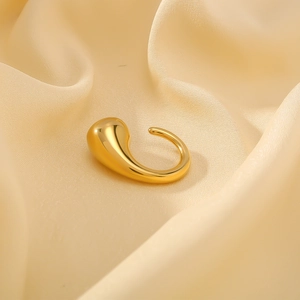 Polished gold teardrop stainless steel ring on beige silk background for women