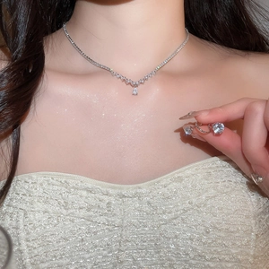 Detail shot of a silver drop pendant necklace and earring set worn on a model